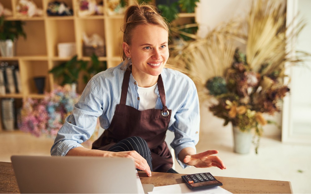 Female business owner smiling, calculating taxes, knowing income tax vs gst