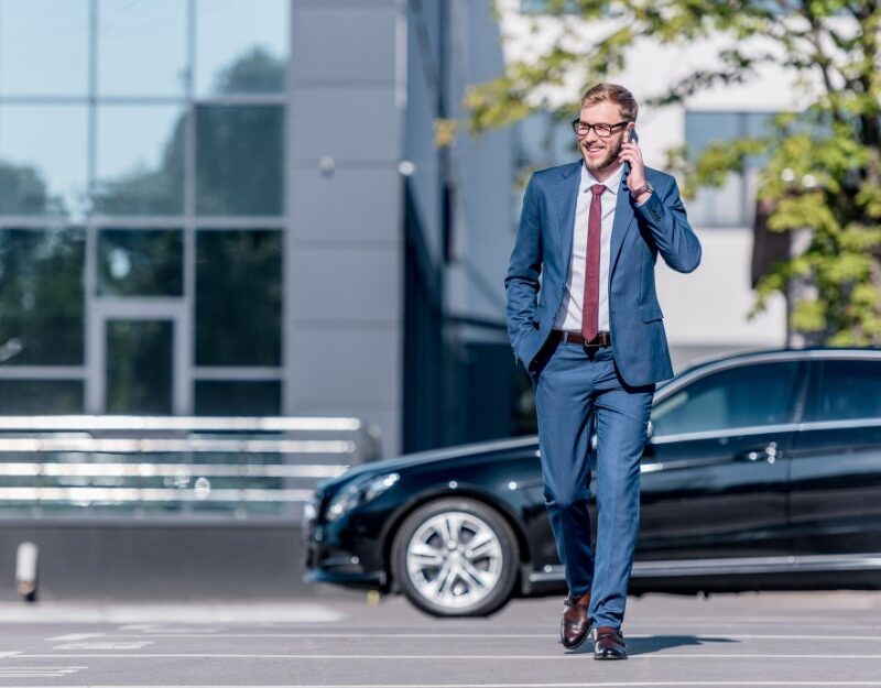 Owner of commercial property talking on the phone with car in the background