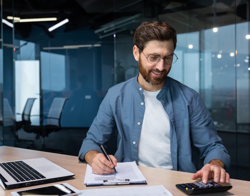 Male business owner calculating taxes to comply with payroll tax contractor rules