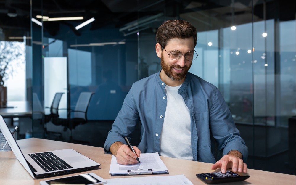 Male business owner calculating taxes to comply with payroll tax contractor rules